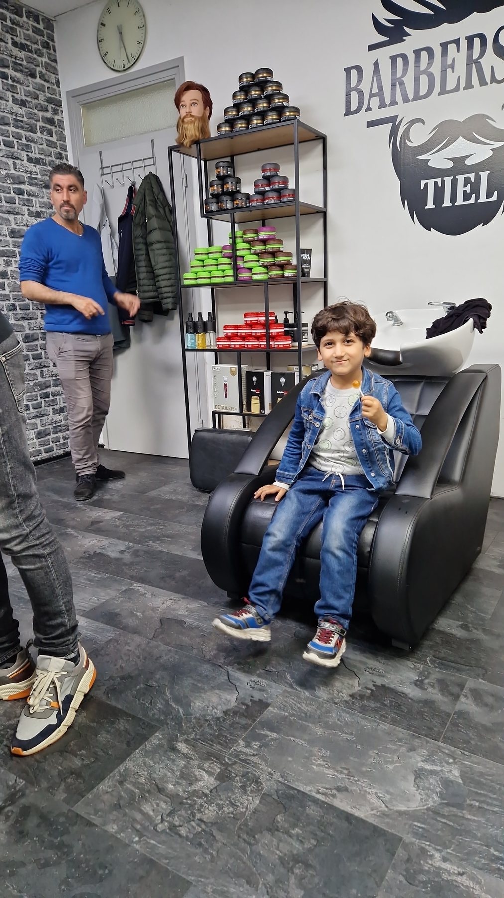 Een jonge klant in de stoel met de barbier ernaast