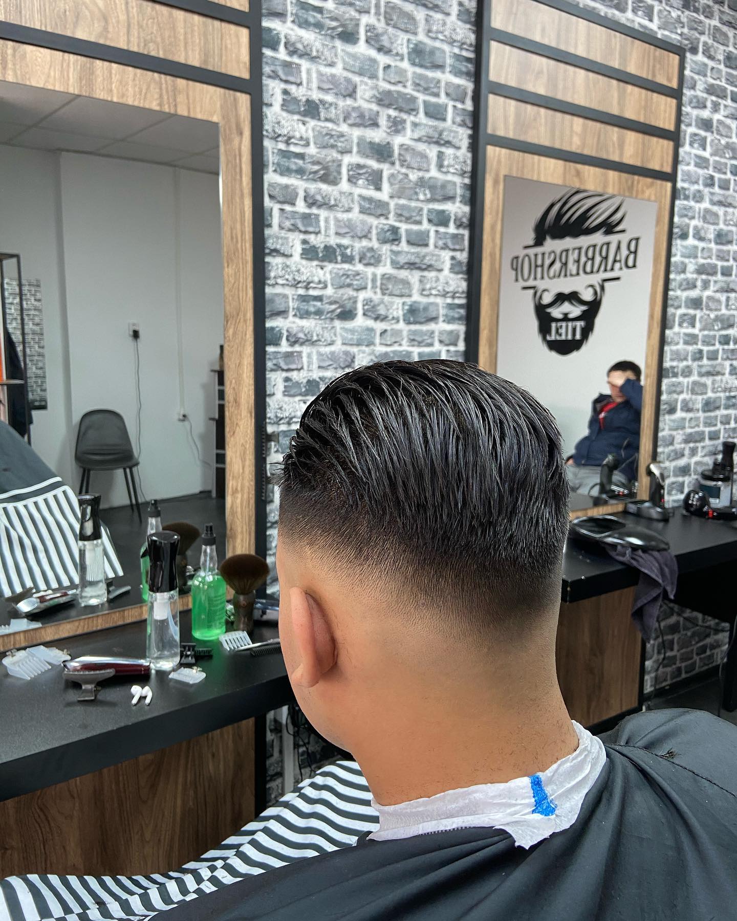 Een strakke fade met naar achteren gekamd haar, van achteren gezien